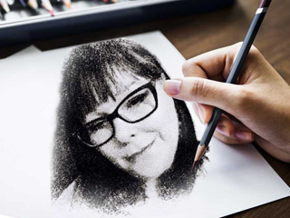 A hand with a pencil in it drawing and image of Soul To Soul Medium Eileen Gonzalez. It is a picture of her head, she has glasses and long hair.