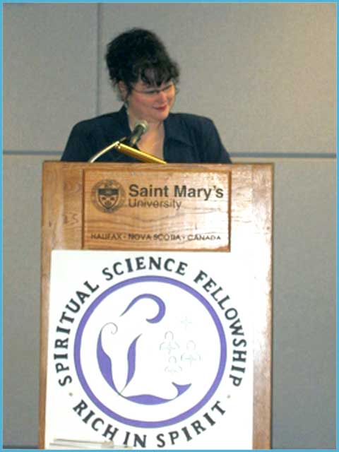 picture of Eileen Casey Gonzalez standing at a platform speaking on behalf of the Spiritual Science Fellowship Halifax